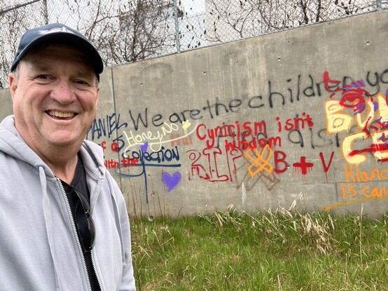 Future Steven Carroll, in front of the large wall of graffiti with a quote