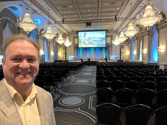 Futurist, Jim Carroll in a sports jacket standing in front of a beautiful stage in Quebec City