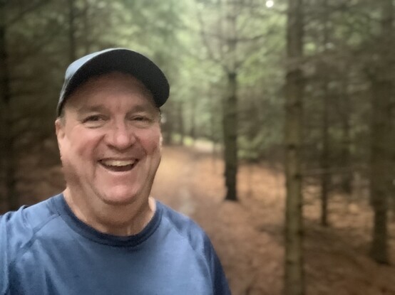future is Jim Carroll, with a big goofy grin on his face as he walks through the forest in the rain