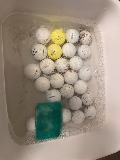 A picture of a bunch of dirty golf balls in a bin